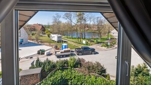 A view from a window with a triangular roof, overlooking a parking area with a camper, a pickup truck, and a car. - in Dänschendorf auf Fehmarn by Interhome (Bannesdorf)