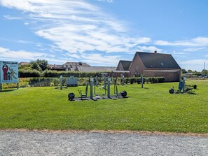 An outdoor fitness park with exercise equipment, a signboard, and a building in the background. - Moderne Ferienwohnung mit Balkon in Strandnähe by Interhome (Friedrichskoog)