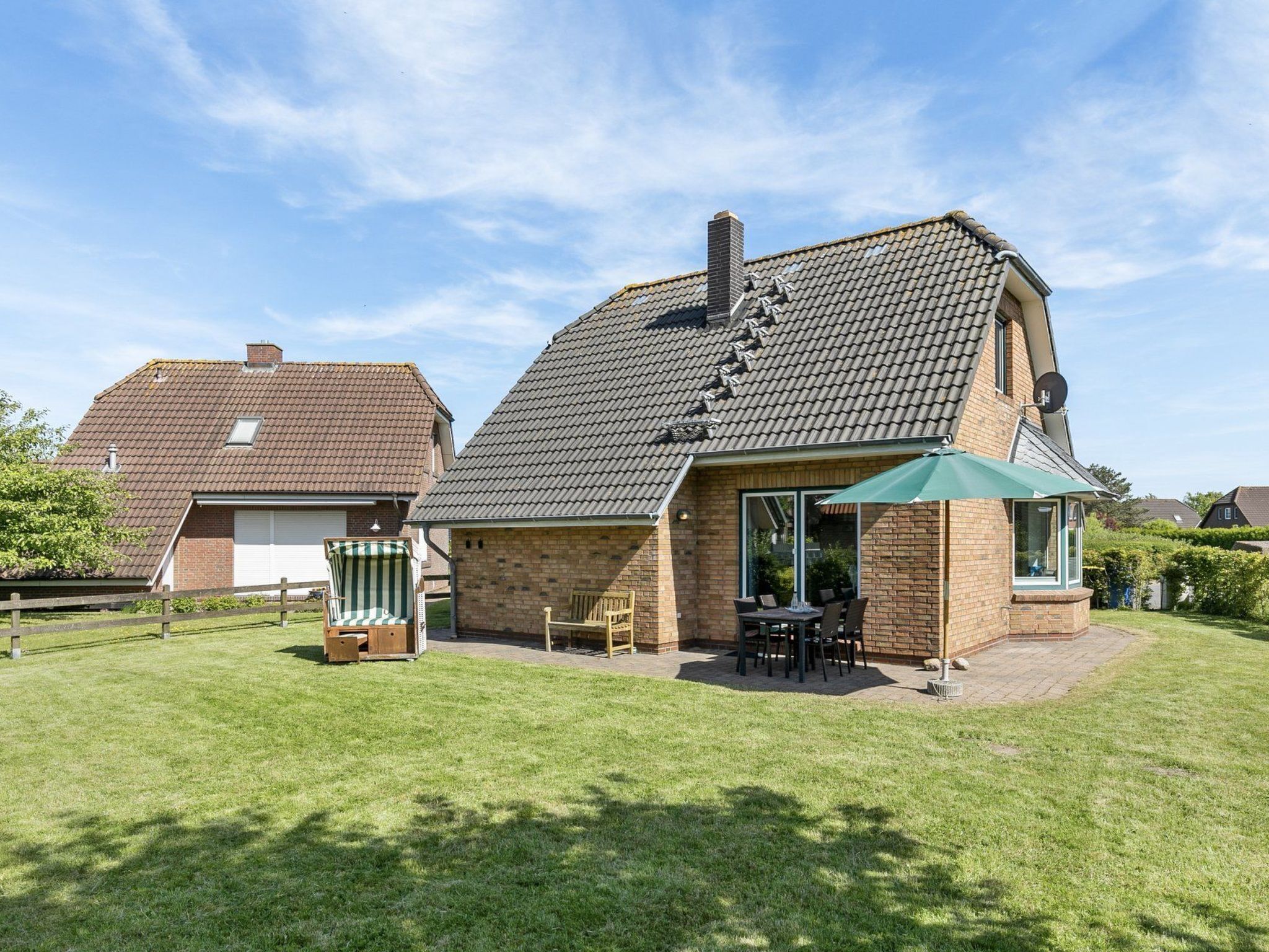A house with a sloped roof, a brick exterior, and a patio with outdoor furniture.