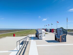 A jet bridge at an airport with a clear sky, grass runway, and flags. - Ferienkate am Deich by Interhome (Friedrichskoog)