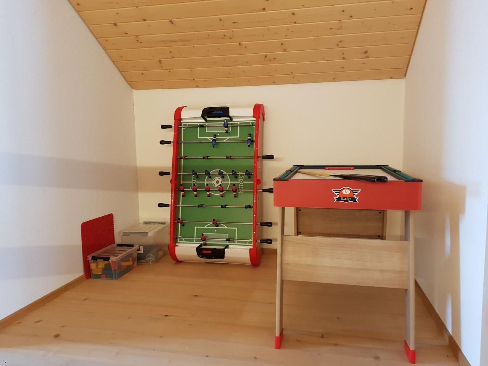 A room with a foosball table and a pool table.