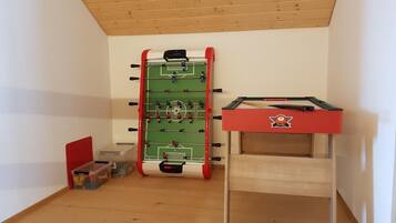 A room with a foosball table and a pool table.