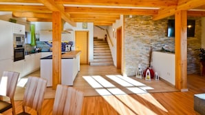 A spacious kitchen with wooden beams, a stone wall, and a staircase leading to another level. - Das Almhaus in Bad St. Leonhard im Lavanttal by Interhome (Klippitztörl)