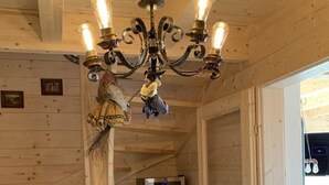 A wooden interior with a chandelier, a wine cooler, and a staircase.