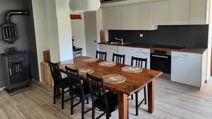 Moderni keittiö, jossa on valkoiset kaapit, musta työtaso ja puinen ruokapöytä mustilla tuoleilla.
