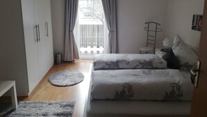 Een slaapkamer met een bed, een kledingkast, een klein tafeltje, een stoel en uitzicht op het omliggende landschap.