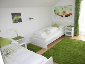 A bedroom with a bed, bedside tables, a nightstand, a green rug, and a wall-mounted picture. - Rosa in Umhausen by Interhome (Umhausen)