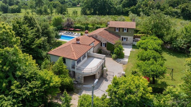 Ein großes Haus mit Swimmingpool, umgeben von üppiger Vegetation und Hügeln.