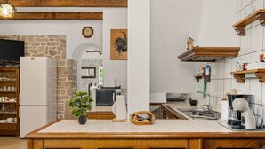 Eine Küche mit Kochinsel, Holzschränken, einer Steinwand und einer Wanduhr.