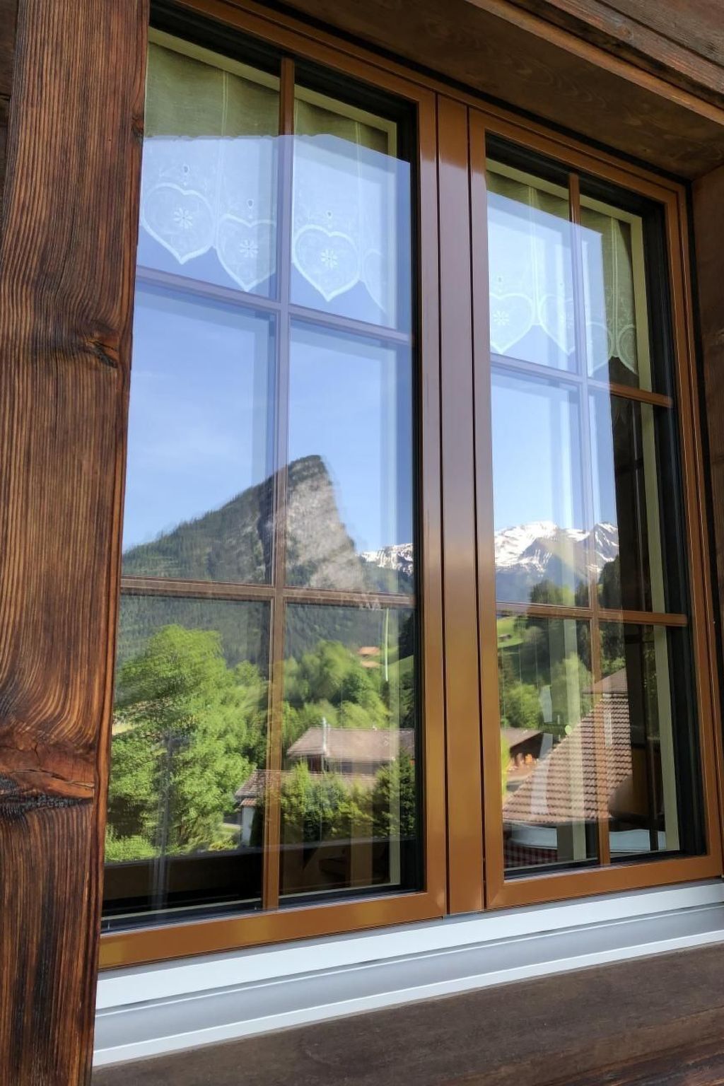 A large window with a view of a mountainous landscape and a forested area.