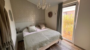 Makuuhuone, jossa on sänky, kattokruunu, ikkuna, jossa on verhot, ja näkymä ulos.