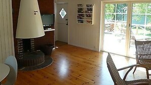 Een woonkamer met een open haard, een televisie en een eethoek met een tafel en stoelen.