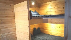 Una cabaña con paredes de madera y una cama literera de dos niveles.