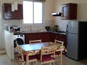 Eine kleine Küche mit Waschmaschine, Kühlschrank, Spüle und Holzausstattung.