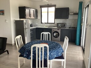 Eine kompakte Küche mit dunklen Schränken, einer Waschmaschine, einer Mikrowelle und einer Essecke mit Tisch und Stühlen.