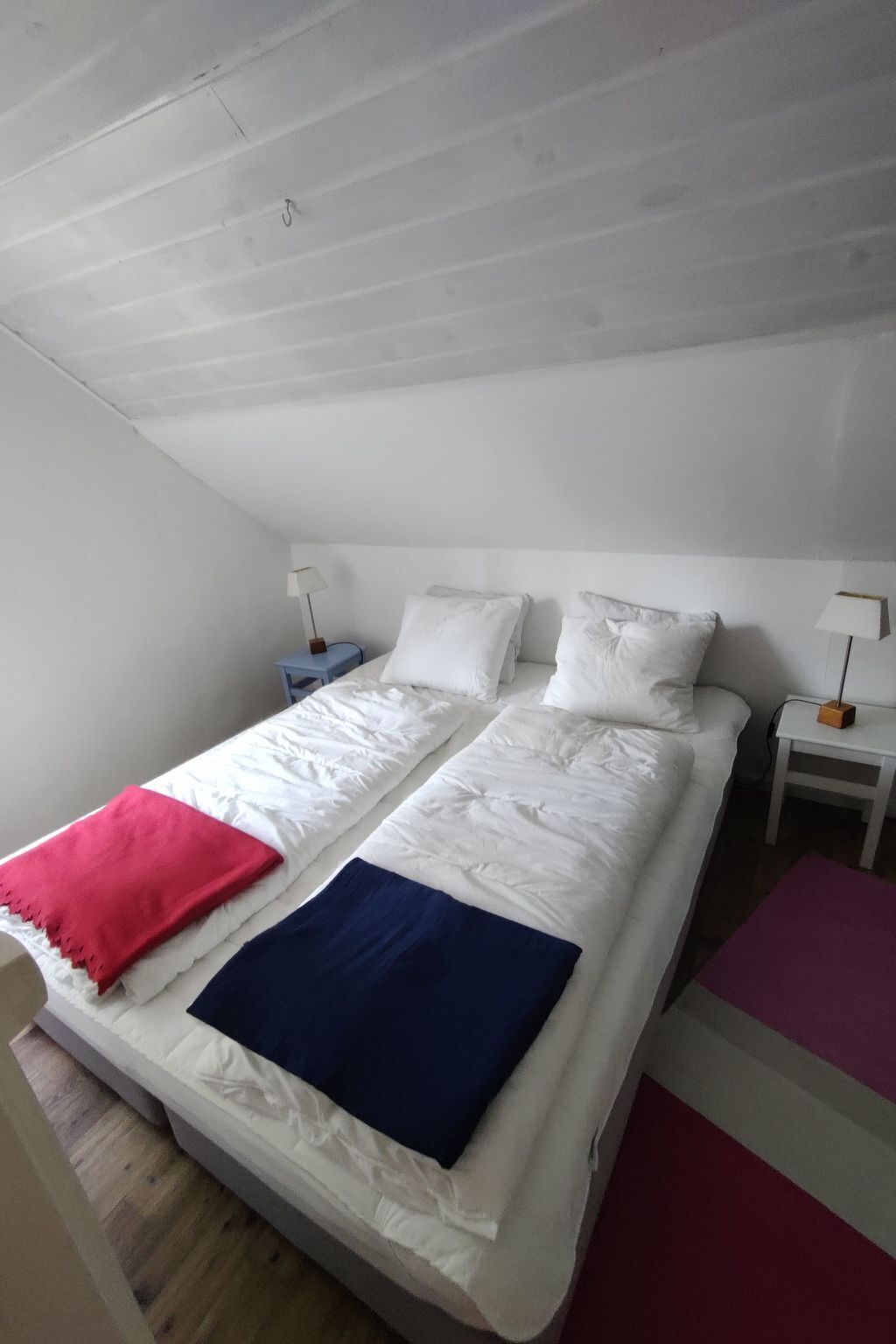 A bedroom with two beds, white bedding, and bedside tables with lamps.