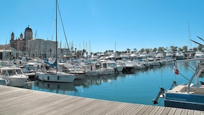 A marina with numerous boats docked, a wooden pier, and a large building with domed architecture in the background. - Die Sonne der Côte d'Azur by Interhome (Saint-Raphaël)