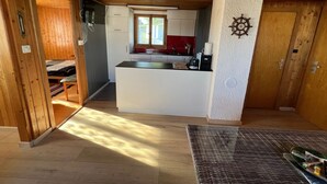Une cuisine compacte dotée d’un îlot central, d’un plafond en bois et donnant sur une chambre.