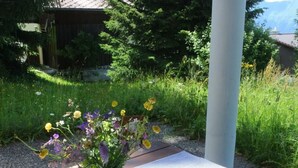 A wooden bench with a white vase of flowers and a bottle of milk on it.