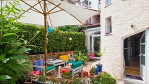 An outdoor patio area with a table and chairs, surrounded by greenery and a stone wall. - Wohnung in Rijeka mit Terrasse und Grill by Interhome (Rijeka)