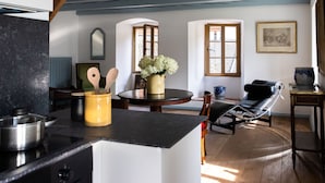A kitchen with a stove, a dining table with chairs, and a wooden ceiling. - Chateau Duplex Ferme by Interhome (Marnand)