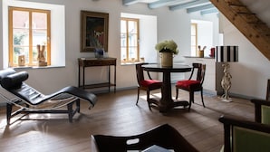 A room with a black leather chair, a wooden table with a vase, and a painting on the wall. - Chateau Duplex Ferme by Interhome (Marnand)