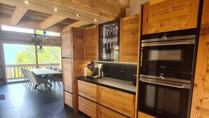 Une cuisine moderne avec des meubles en bois, un four encastré et une machine à café.
