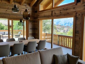 Une cabane en bois avec un coin repas, de grandes fenêtres et une vue sur les montagnes.
