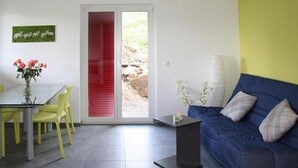 A modern living room with a blue sofa, yellow chairs, a glass table, and a red sliding door. - Appartement dans une ferme rénovée by Interhome (Le Mont-Pèlerin)