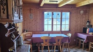 En interiör med träinredning, ett matområde, ett träpanelat tak och stora fönster.