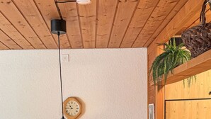 A wooden dining area with a bench, a clock, and a hanging light fixture. - Rottal 4 Bett Wohnung by Interhome (Lauterbrunnen)