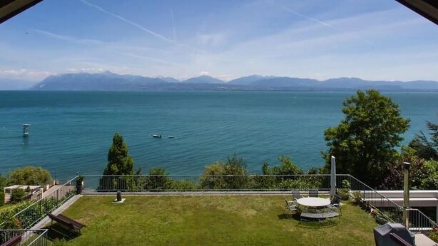 A view from a balcony overlooking a lake with mountains in the distance. - Chalet am See in St-Prex by Interhome (Saint-Prex)
