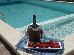 A tray with a bottle of champagne, two glasses, and a plate of strawberries by a pool. - mit beheiztem Pool und Meerblick by Interhome (Umag/Savudrija)