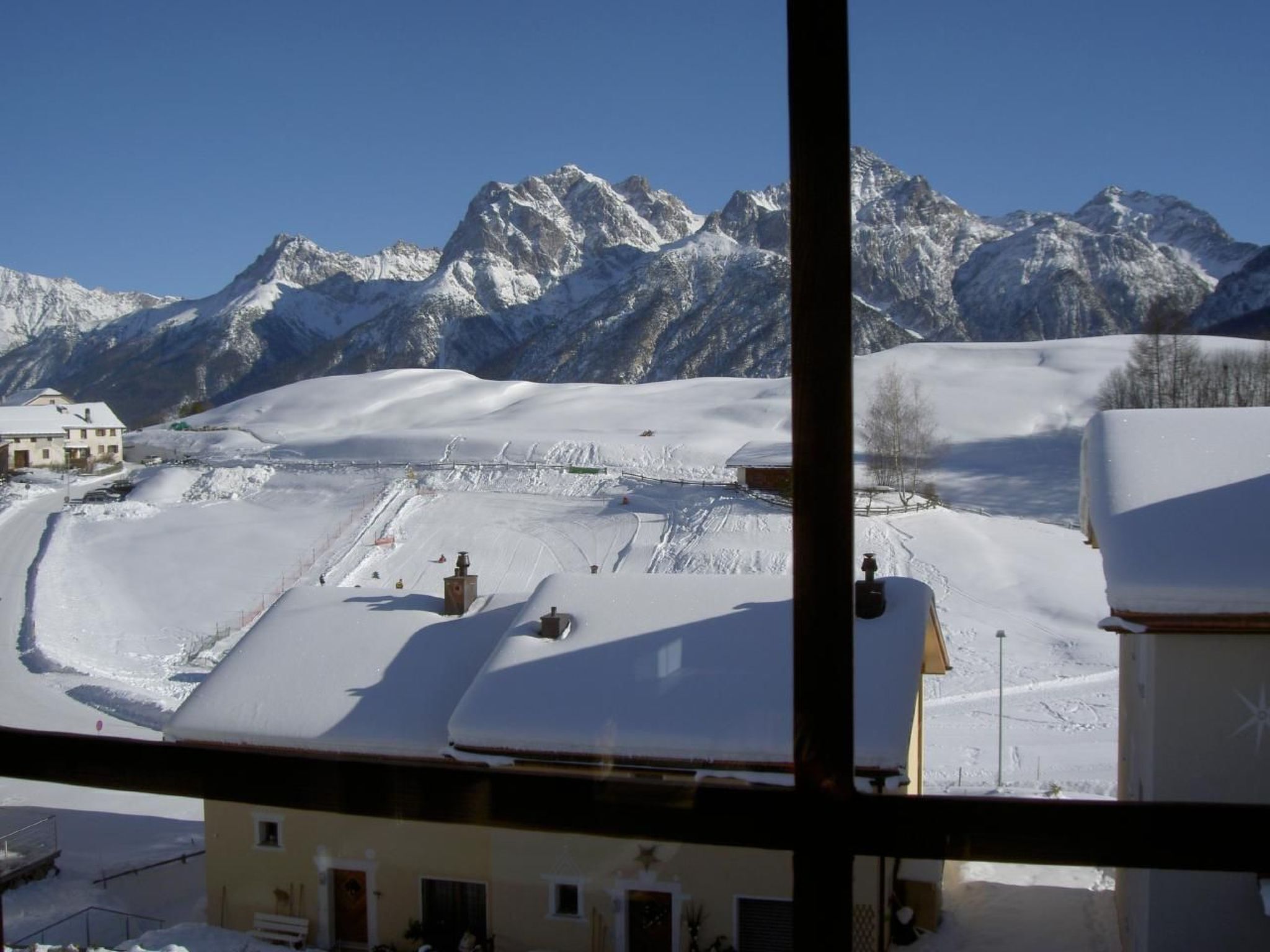 A snow-covered mountain landscape with a ski resort in the foreground, including ski lifts and a building.