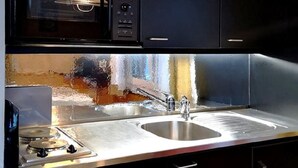 A modern kitchen with dark cabinetry, a stainless steel sink, and a microwave. - Chalt "Arve" by Interhome (Riederalp)