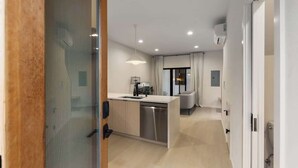 A modern kitchen with a central island, a dining area with a sofa, and a large window with curtains. - Modern Seattle Stay • Rooftop Views & Ensuite BRs (Seattle)
