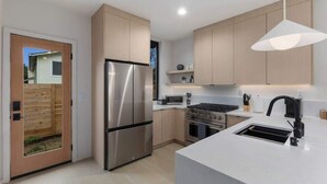 A modern kitchen with stainless steel appliances, a central island, and a pendant light. - Modern Seattle Stay • Rooftop Views & Ensuite BRs (Seattle)