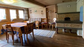 Uma área de refeições acolhedora, com mobiliário de madeira, uma mesa com toalha estampada e uma lareira com detalhes decorativos.
