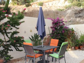 An outdoor patio with a table and chairs, surrounded by potted plants and flowering shrubs. - MYHIDEAWAY APARTMENT mit kostenlosem WiFi by Interhome (Peyia)