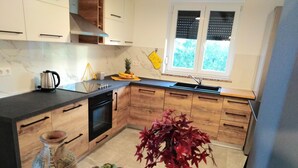 A modern kitchen with wooden cabinets, a black countertop, a stove, and a potted plant. - mit Terrasse, Grill und Garten by Interhome (Umag/Juricani)