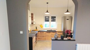 A modern kitchen with wooden cabinets, a central island, and pendant lighting. - mit Terrasse, Grill und Garten by Interhome (Umag/Juricani)