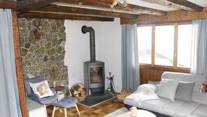 Un salon chaleureux avec un mur en pierre, une cheminée, un canapé, une petite table et un fauteuil.