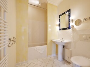 Un baño con bañera, lavabo, inodoro y espejo con luces.