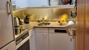 A compact kitchen with white cabinets, a stainless steel stove, and a sink. - Hüttbödeli by Interhome (Brienz)