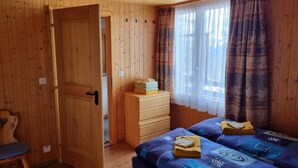 A wooden room with a bed, a chair, a dresser, and a door. - Hüttbödeli by Interhome (Brienz)