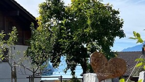 A garden with heart-shaped metal sculptures, a stone wall, and a building with a tiled roof in the background.
