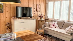 A wooden-paneled room with a TV, sofa, and a small table.
