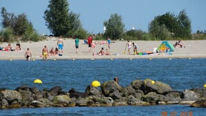Ranta, jossa on ihmisiä, teltta ja kivikkoinen rantaviiva.