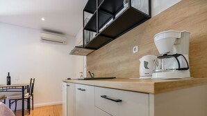 Pieni, käytännöllinen keittiö, jossa on puinen työtaso, kahvinkeitin ja pöydällä viinipullo.