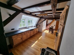 Eine Küche mit Holzausstattung, einer schwarzen Arbeitsplatte und Blick auf einen Garten durch große Fenster.